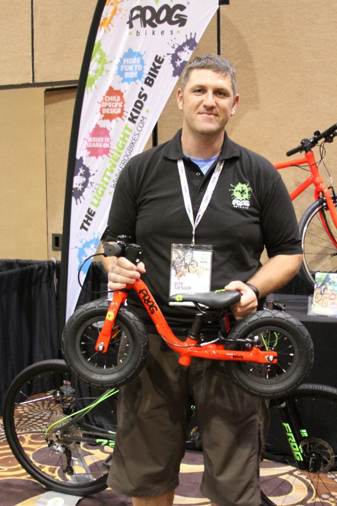 ITS NEVER TO EARLY TO START YOU TODDLER OUT ON BIKES. JEFF GIESLER FROM FROG BIKES HOLDING THEIR SMALLEST BIKE FOR YOUR FUTURE MTB CHAMP.
