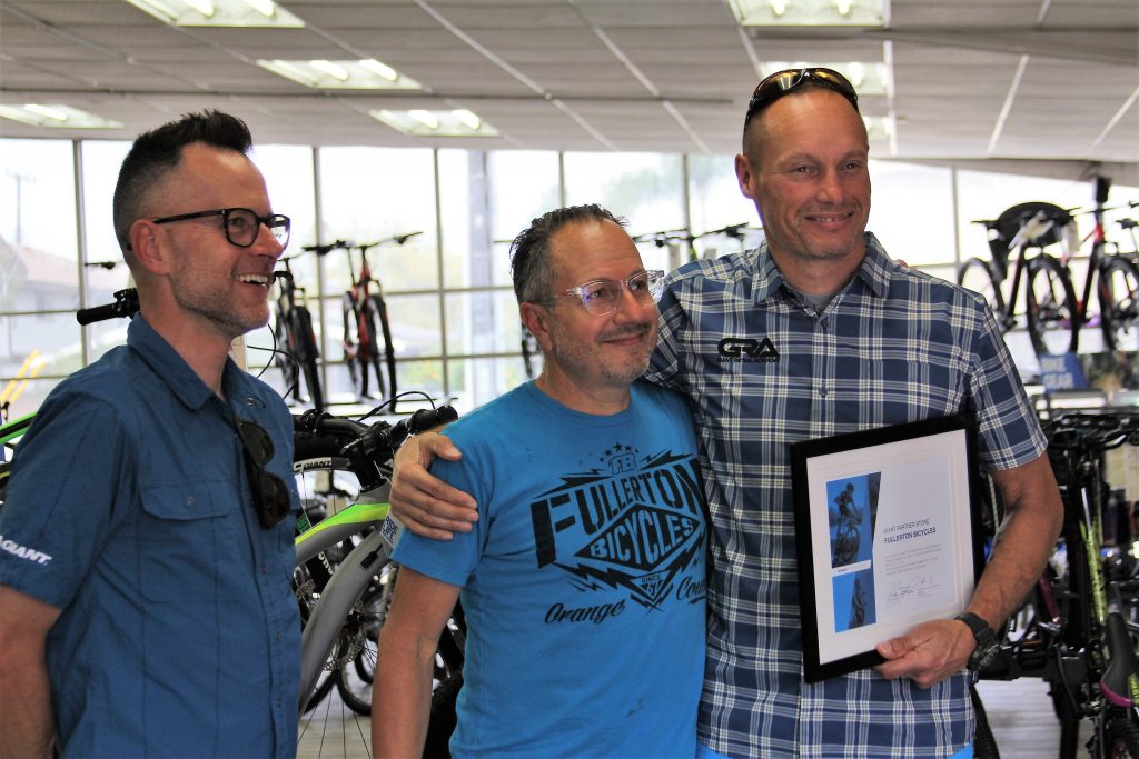 GIANT GENERAL MANAGER JOHN THOMPSON (R) AND GIANT REGIONAL MANAGER ERIC WOODS (L) PRESENTING MIKE FRANZE WITH A PLAQUE CERTIFYING FULLERTON BICYCLE AS THE NEWEST GIANT RETAIL PARTNER.